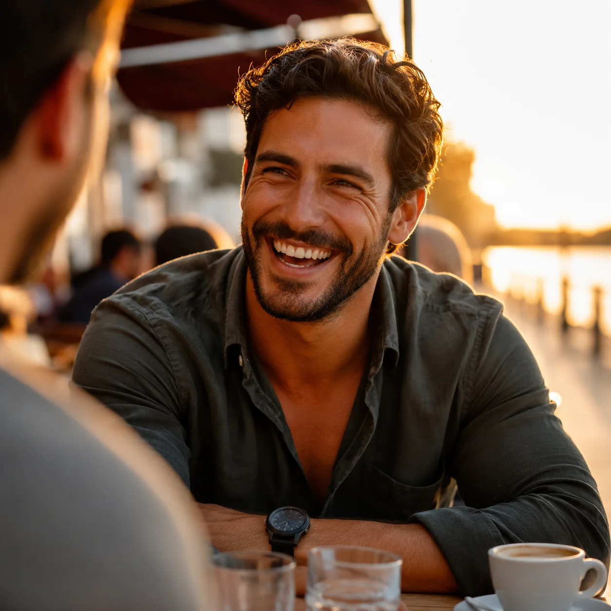 Man laughing during a real first date at an outdoor cafe — the kind of moment strong Hinge prompts and photos lead to